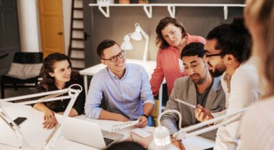 En grupp kollegor som på ett kontor, vid samma skrivbord.
