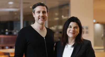 En man och en kvinna tittar in i kameran. De ler.