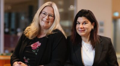 Två kvinnor tittar in i kameran och ler.